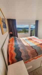 ein Schlafzimmer mit einem farbenfrohen Bett und einem Fenster in der Unterkunft Neu 55min von Oslo Ferienhaus mit Aussicht Sauna Wassersport in Berger