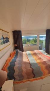 ein Schlafzimmer mit einem farbenfrohen Bett und einem Fenster in der Unterkunft Neu 55min von Oslo Ferienhaus mit Aussicht Sauna Wassersport in Berger
