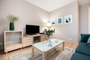 sala de estar con TV y mesa de centro en Metro Stokłosy Blue Mint Apartment, en Varsovia