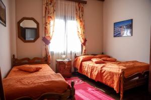 a bedroom with two beds and a mirror and a window at Mprizis Rooms in Elati Trikalon