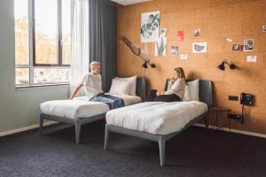 a man and woman sitting on beds in a room at Conscious Hotel Amsterdam City - The Tire Station in Amsterdam