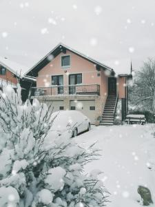 dom pokryty śniegiem z samochodem zaparkowanym na podjeździe w obiekcie Holiday Home Lana w mieście Fužine