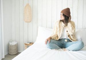 a woman sitting on a bed wearing a hat at The Surfside Hotel in Stratford