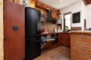 um frigorífico preto numa cozinha com armários de madeira em Gdynia Centrum Apartament przy Promenadzie by Renters em Gdynia