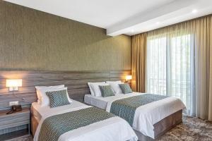 a hotel room with two beds and a window at Vinum Hotel in Tbilisi City