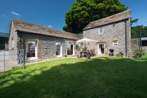 a stone house with a large lawn in front of it at Long Roods cottage in Bakewell