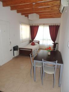 a room with a table and chairs and a bed at C&M Alquiler temporario y Rent a Car in Las Heras