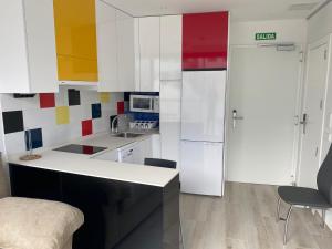 Ekilibrio Hotel & Apart-Suites في مدريد: مطبخ فيه دواليب بيضاء وثلاجة بيضاء