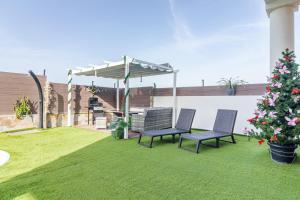 a patio with two chairs and an umbrella and a christmas tree at Villa Samperez Piscina Jardin 5 Dormitorios 12 Personas in Las Palmas de Gran Canaria +49 photos