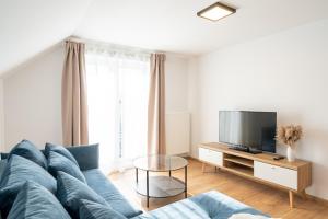 a living room with a blue couch and a tv at Apartmány Oravskie in Zuberec
