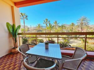 een blauwe tafel en stoelen op een balkon met palmbomen bij 797 Holiday Rentals- Apartamento en Hotel Sunset Beach frente al mar in Benalmádena