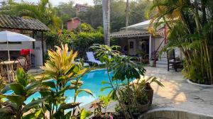 a pool in a yard with plants and a house at Chez Marine Guest House in Búzios