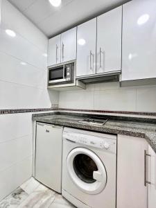 a white kitchen with a washing machine and a microwave at 797 Holiday Rentals- Apartamento en Hotel Sunset Beach frente al mar in Benalmádena