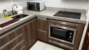eine Küche mit einer Spüle und einer Mikrowelle in der Unterkunft Flat Brookfield Towers 2309 in Goiânia