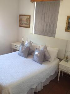 a bedroom with a bed with white sheets and pillows at Camdeboo Cottages in Graaff-Reinet