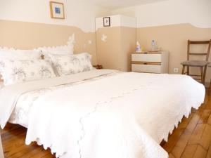 1 dormitorio con 1 cama blanca y 1 silla en La Grande Maison, en Seine-Port