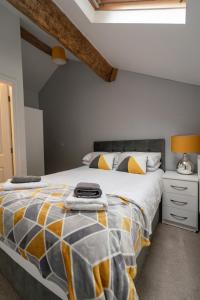 ein Schlafzimmer mit einem großen Bett mit einer gelben und grauen Bettdecke in der Unterkunft Quinta Cottage in Soutergate