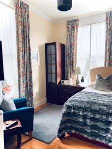 a bedroom with a bed and a chair and windows at Ashleigh House in Carlisle