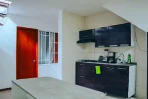 una cocina con armarios negros y una puerta roja en Hermoso y acogedor apartamento, en Cali