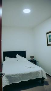 a white bed in a room with a white light at Hermoso y acogedor apartamento in Cali