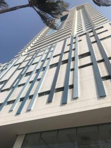 a tall white building with windows and a palm tree at Cartagena Palmetto Beach Bella Vista in Cartagena de Indias