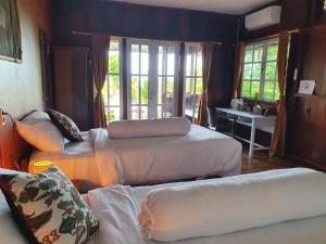a bedroom with three beds and a table and windows at Amban Beach House in Manokwari