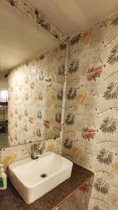 La salle de bains est pourvue d'un lavabo et d'un mur. dans l'établissement Pappi Chulo Vagator, à Vagator