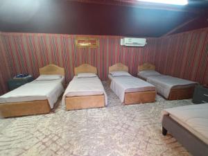 drie bedden in een kamer met een muur bij The Dunes Farm House RAK in Masāfī