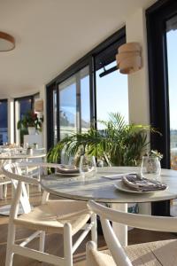 纽基Porth Beach Hotel的有白色桌椅和窗户的餐厅