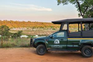 um jipe verde estacionado numa estrada de terra batida em Kruger Riverside Lodge - No Load-shedding em Marloth Park