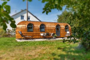 een houten huis met stoelen en een tafel ervoor bij Auszeitgarten - Urlaub im Tinyhaus im Herzen von Oberschwaben in Aulendorf