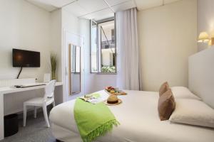 a white hotel room with a bed and a desk at Hôtel P.L.M. in Cannes