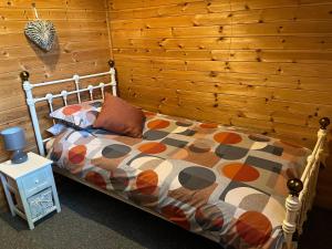 a bedroom with a bed and a wooden wall at Wye View Lodge, Hay View Lodges in Hereford