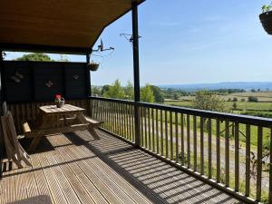 une terrasse en bois avec une table et un banc. dans l'établissement Wye View Lodge, Hay View Lodges, à Hereford