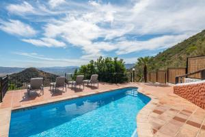 a swimming pool with chairs and a mountain at La Casa de Alejandro in El Chorro