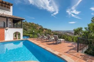 a swimming pool with chairs next to a house at La Casa de Alejandro in El Chorro