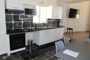 a kitchen with white cabinets and a stone wall at Self-Catered Apartment With Pool in Krugersdorp
