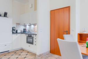 eine Küche mit weißen Schränken und einer Holztür in der Unterkunft Villa Seestern Whg. 760 in Binz