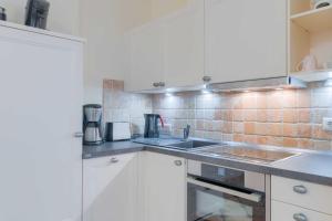 eine Küche mit weißen Schränken und einer Spüle in der Unterkunft Villa Seestern Whg. 760 in Binz + 13 Fotos