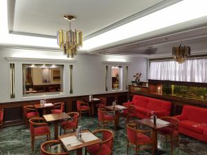 a restaurant with red furniture and tables and chairs at Savoy Hotel in Piraeus