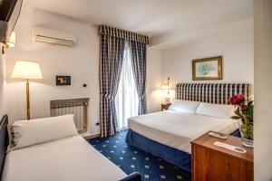 um quarto de hotel com duas camas e uma mesa em Hotel Napoleon em Roma