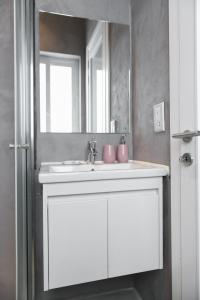 La salle de bains est pourvue d'un lavabo blanc et d'un miroir. dans l'établissement Privilege Suite, à Tal-Pietà