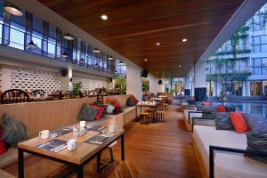 a restaurant with couches and tables and chairs at Hotel NEO+ Kuta Legian by ASTON in Legian