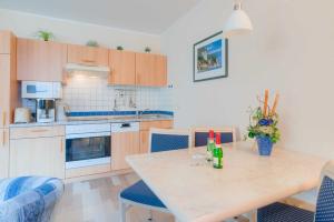 cocina con mesa de madera y sillas azules en Haus Margarete Whg_ 2 en Binz