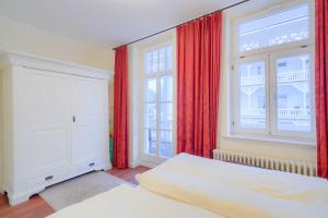 Schlafzimmer mit einem Bett und einem Fenster mit roten Vorhängen in der Unterkunft Villa Aegir Whg. 4 in Binz