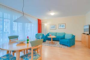 ein Wohnzimmer mit einem Tisch und blauen Stühlen in der Unterkunft Villa Elfeld 2 Whg. 717 in Binz