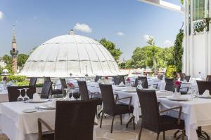 un restaurante con mesas y sillas blancas y sombrilla en Ottoman Hotel Imperial-Special Category, en Estambul
