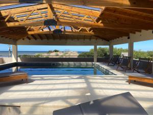 a swimming pool with benches and a wooden roof at Costanera Mar Hotel & Suites in San Clemente del Tuyú