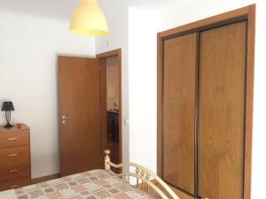 1 dormitorio con armario de madera y cama en Apartamento T2 - Grândola Vila Morena, en Grândola