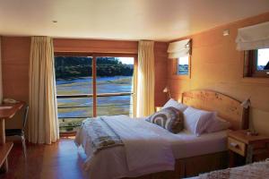 um quarto com uma cama e uma grande janela em Palafito 1326 Hotel Boutique Chiloé em Castro